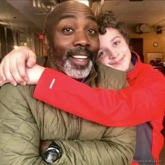 Smiling boy hugging his foster father warmly in a café setting.