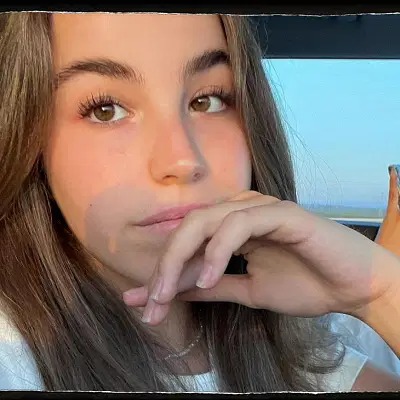 Close-up portrait of a young woman looking thoughtful, resting her hand on her face.