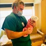 Doctor gently holding a newborn baby in a hospital room, symbolizing care and hope.