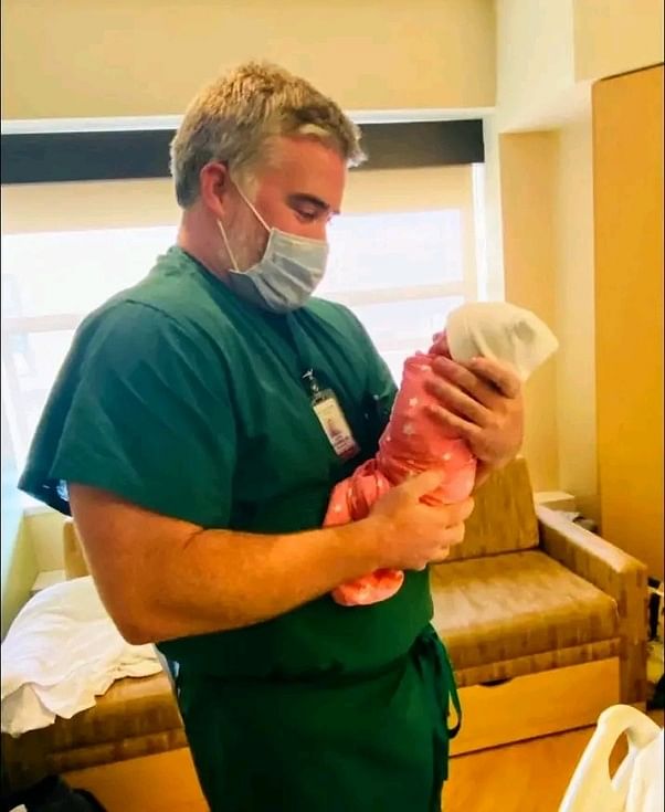 Doctor gently holding a newborn baby in a hospital room, symbolizing care and hope.