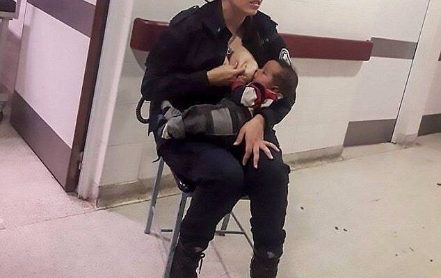 Policewoman in uniform breastfeeding an abandoned baby in a hospital corridor.