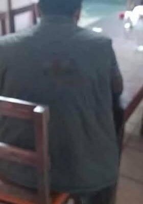 Man sitting alone at a restaurant table, seen from behind.