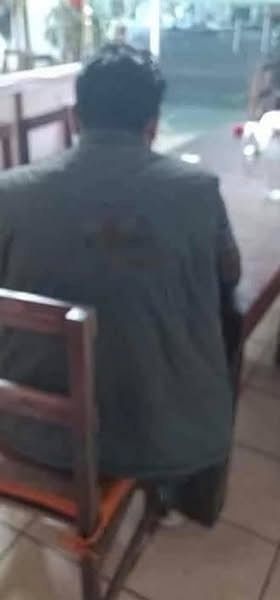 Man sitting alone at a restaurant table, seen from behind.